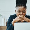 A person concentrating on their laptop with concern.